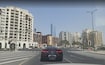 Al Jaddaf_a car is driving down the street in front of tall buildings